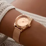 Reloj Guess modelo GW0842L3, color oro rosa, con caja redonda de 30mm, bisel texturizado, dial con números romanos y un diamante a las 12. Brazalete de malla milanesa ajustable.