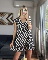 Vestido corto con estampado geométrico en blanco y negro, escote en V y mangas cortas con volados. Presenta un volado en el ruedo.