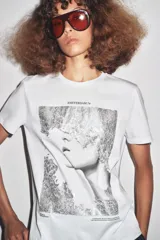 Camiseta blanca de corte recto y manga corta, con estampado frontal de una fotografía en blanco y negro y texto "Amsterdam 74".