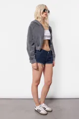 Campera gris de frisa con lavado acid, silueta oversize, manga ranglan con recortes verticales, puños de frisa con recortes de rib y mitones, cintura de rib al tono, capucha forrada al tono en su interior y bolsillo canguro. Acceso frontal mediante cierre desmontable metálico YKK con tiracierre personalizado con logo de marca.