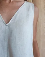 Vestido largo color crudo, sin mangas y con escote en V. Presenta aberturas laterales en el ruedo y bolsillos laterales a la altura de la cadera.