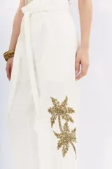 Pantalón blanco de tiro alto con corte paper bag, cintura con lazo a tono y bordado de lentejuelas y piedras en el lateral.