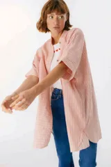 Camisa color salmón con rayas verticales blancas, cuello mao, manga corta con terminación en puño, botones de metal a la vista y tajos laterales.