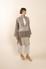 Camisa larga color beige con cuello mao, manga larga con tajo y botón. Diseño con bloques de tela con textura.