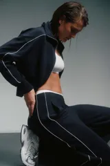 Conjunto deportivo azul marino con detalles de ribete blanco. Incluye una campera corta con cierre y un pantalón de corte recto.