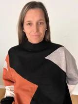 Suéter tejido con diseño geométrico en bloques de color negro, gris, blanco y terracota. Tiene cuello alto tipo polera y corte relajado.
