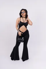 Mono enterizo negro ajustado al cuerpo, con escote halter y abertura en el abdomen.