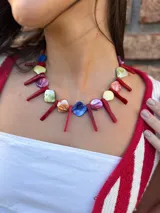 Collar corto con cuentas de nácar teñidas en colores y barritas de coral. Se cierra con cadena de acero quirúrgico y ganchito para regular el largo.