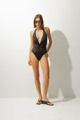 Malla enteriza negra con escote halter y detalle de nudo en el centro del busto.