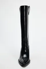 Bota alta negra de cuero sintético, estilo cowboy, con punta fina y tacón geométrico.