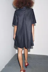 Vestido corto de Zara Woman Collection confeccionado en tejido tipo denim. Tiene cuello solapa, manga corta, bolsillos delanteros ocultos, bajo evasé y cierre frontal con botones.