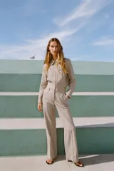 Chaqueta corta color beige con cuello solapa, manga larga y cierre frontal con cremallera.