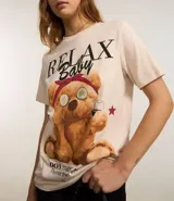 Remera de algodón color crema con estampa de oso de peluche con anteojos y pañuelo rojo en la cabeza.
