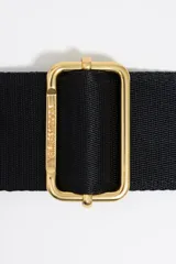 Correa bandolera ajustable de tejido negro con el logo de Bimba y Lola en jacquard. Tiene detalles en piel vacuna negra y herrajes metálicos dorados.