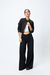 Pantalón de jean negro de calce ultra wide, tiro medio y pierna extra ancha con ruedo desflecado.