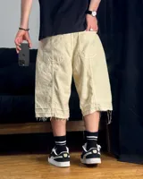Bermuda de corte baggy color beige crema, con costura vertical trasera en cada pierna y detalle artesanal visible en el bajo. Incluye un cordón extra confeccionado en la misma tela.