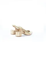 Zapato de cuero color dorado, con punta fina, talón descubierto y tira trasera ajustable.
