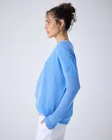 Sweater de cashmere color lila con cuello en V, corte oversize, mangas largas, hombros caídos y terminaciones acanaladas.