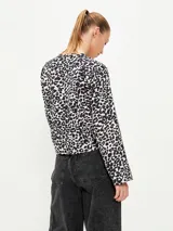 Blusa negra con estampado animal print en blanco y marrón, escote en V con lazo ajustable y mangas largas acampanadas.