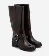Bota biker de caña alta color marrón oscuro, con puntera redonda, taco bajo y detalle de hebilla con aro metálico en el lateral.