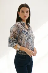 Camisa celeste con estampado abstracto en tonos marrones y azules, de corte clásico, cuello camisero y mangas largas con puños abotonados.