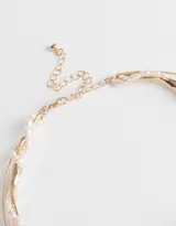 Gargantilla rígida dorada con detalle de perlas.