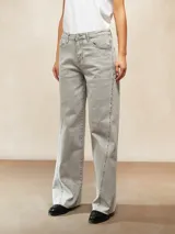 Jean de mujer color gris claro lavado, tiro alto, corte ancho y recto (wide leg). Presenta costuras marcadas en el frente de las piernas con pequeños detalles metálicos o tachas a lo largo de la costura.