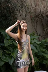 Vestido corto de color verde azulado brillante, con escote halter, espalda descubierta, abertura en la cintura y falda con volados.