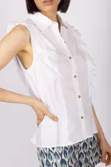 Blusa amarilla con botones y detalles de volantes en los hombros.