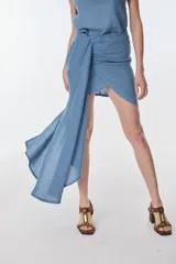 Conjunto de camisa celeste de mangas largas abullonadas y falda turquesa con detalle fruncido y lazo en el lateral.