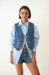 Chaleco denim con botones plateados en la parte delantera y bolsillos simulados.