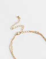 Collar corto dorado multicadena con piedras de colores y dije ovalado con una rosa esmaltada en blanco.