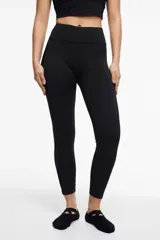 Calza deportiva larga negra con cintura alta, detalles de transparencias laterales en tul y bolsillos laterales.