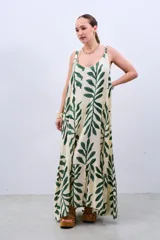 Vestido largo color crudo con estampado de hojas verdes, de corte amplio y breteles finos.