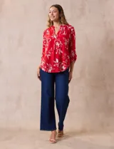 Blusa de gasa roja con estampado floral blanco, cuello a la base con escote en V y mangas 3/4 regulables con presilla y botón.