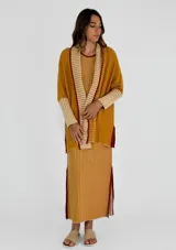 Vestido largo a rayas verticales color gris y blanco, con cuello en V y ribete amarillo. Presenta aberturas laterales con ribete amarillo.