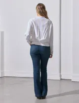 Chaqueta de lino a rayas verticales amarillas y celestes, con cuello a la base, abertura central con botones, bolsillos delanteros y ruedo con jareta de ajuste.