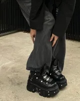 Borcego negro de cuero con plataforma track y detalles metálicos. Ajuste con cordones y hebillas.