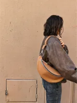 Riñonera de cuero color marrón claro, con correa regulable y cierre superior.