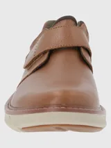 Zapato de cuero color marrón claro con ajuste de velcro y suela de goma color crema.