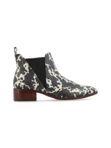 Botín Chelsea de cuero con estampado animal print en blanco y negro, elásticos laterales texturizados, punta semi-redondeada y taco bajo de madera.