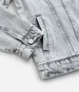 Campera de jean de hombre, modelo regular, con efecto desteñido en tonos grises claros. Presenta cuello inglés, manga larga, abotonado frontal y dos bolsillos con solapa y botón en el pecho.