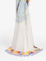 Pareo rectangular de algodón con estampado de una medusa en tonos celeste y amarillo, bordeado con un diseño de cuadrados de colores y flecos lilas.