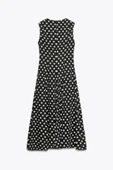 Vestido midi negro con estampado de lunares blancos, cuello redondo y sin mangas.