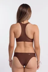 Top de bikini deportivo color marrón chocolate, estilo nadador, con cuello alto y cierre frontal de cremallera roja. Presenta costuras de realce en rojo en los laterales y sisas.