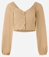 Blusa cropped color beige con escote corazón, mangas largas abullonadas con puños elásticos, botones frontales y detalle de volados en el ruedo.