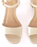 Sandalias de tacón color crema, con capellada y forro de cuero, plantilla de cuero, taco cuadrado y pulsera con hebilla al tobillo.