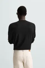 Jersey color topo de corte amplio, tejido en hilatura con mezcla de viscosa. Tiene cuello redondo, manga larga y terminaciones en rib.