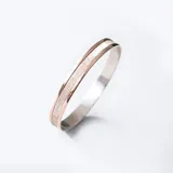 Pulsera rígida de plata con una banda central esmerilada y bordes de oro amarillo 9k. Se puede grabar con nombre y fecha.