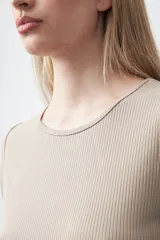 Remera de manga corta color beige claro, confeccionada en tejido acanalado elástico, con cuello redondo.